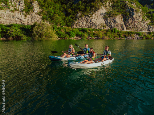 A group of friends enjoying fun and kayaking exploring the calm river, surrounding forest and large natural river canyons during an idyllic sunset.