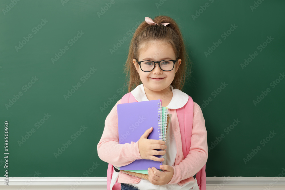 Happy little school child with notebooks near chalkboard Happy little school child with notebooks near chalkboard