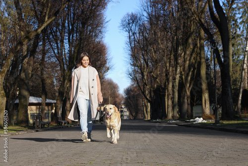 Young woman walking with adorable Labrador Retriever on sunny day outdoors. Space for text