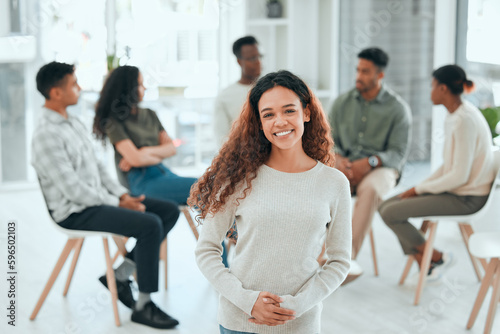 I wouldnt be here without my support group. Shot of an attractive young woman standing while her support group talk behind her.