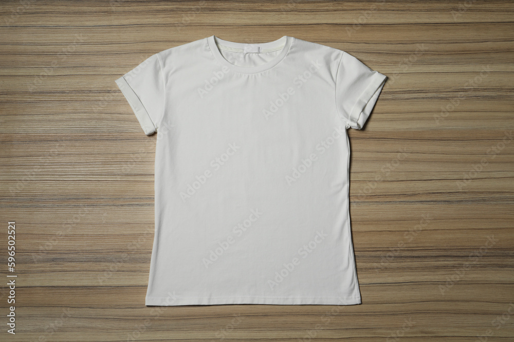 Stylish white T-shirt on wooden table, top view Stylish white T-shirt on wooden table, top view