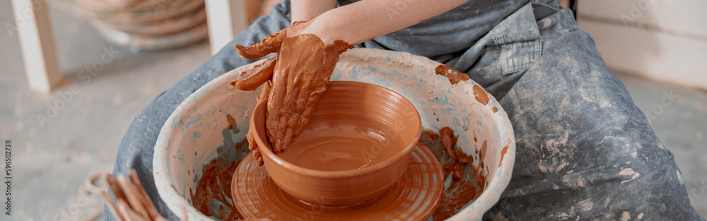 Young woman works on pottery wheel in atelier