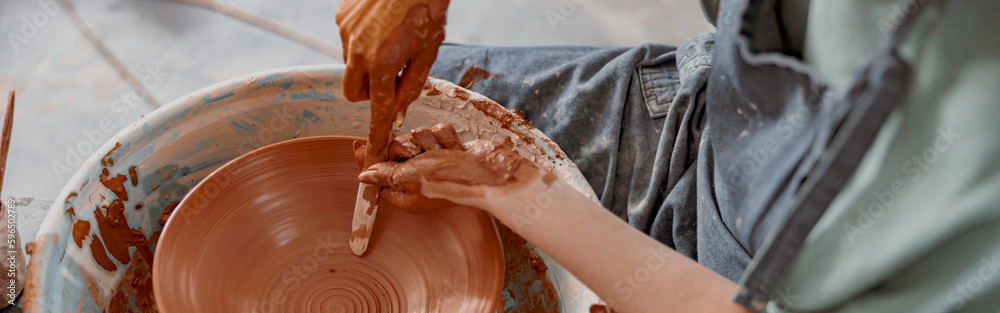 Young potter working on potter wheel in workroom Young potter working on potter wheel in workroom