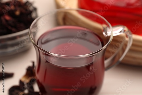 Cup of delicious hibiscus tea on white table, closeup