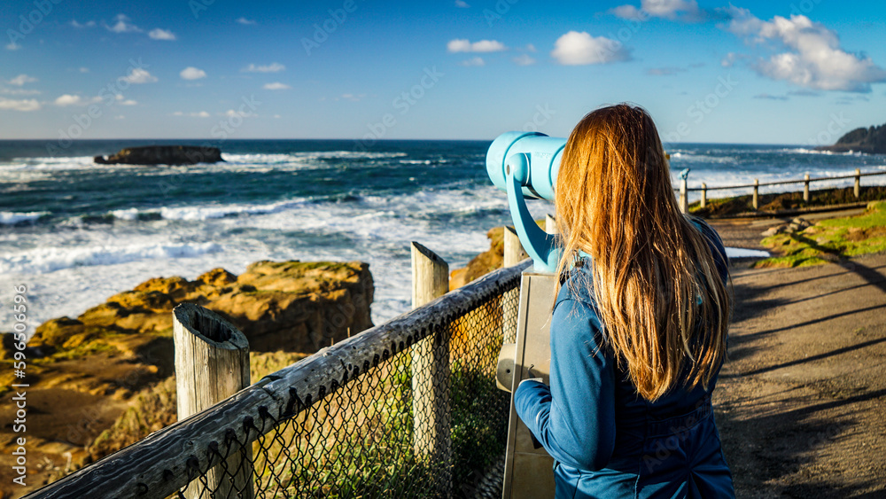 Woman views ocean through telescope