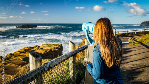 Woman views ocean through telescope