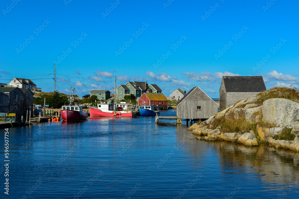 Scenic Peggy's Cove, Nova Scotia, is a quaint fishing village on the edge of a rocky coastline. The storage buildings are colored red, green, and blue color. The summer sky is blue with white clouds. Scenic Peggy's Cove, Nova Scotia, is a quaint fishing village on the edge of a rocky coastline. The storage buildings are colored red, green, and blue color. The summer sky is blue with white clouds.