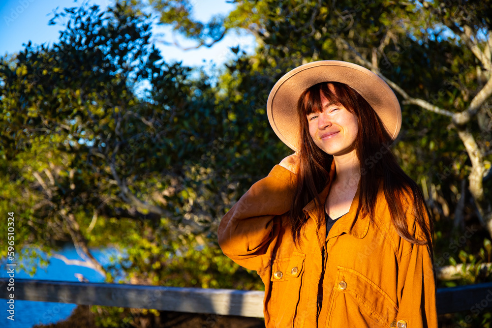 Portrait of beautiful smiling girl wearing hat with mangrove forest and river in background. Nudgee Beach Reserve, Brisbane, Queensland, Australia 