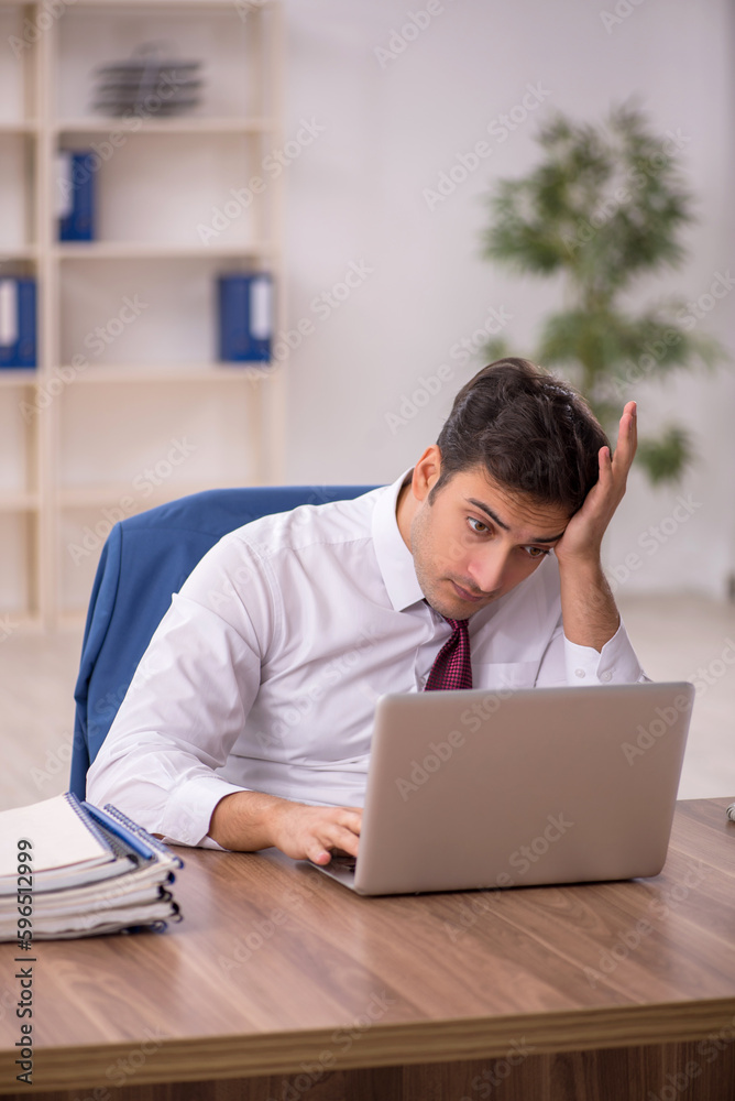 Young male employee and too much work in the office Young male employee and too much work in the office