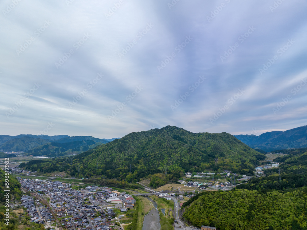 Cloud pattern over small Japanese town by river and green mountain