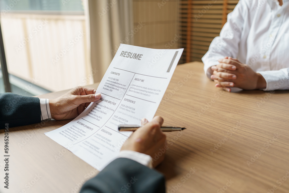 Examiner reading a resume during job interview at office Business and human resources concept Examiner reading a resume during job interview at office Business and human resources concept