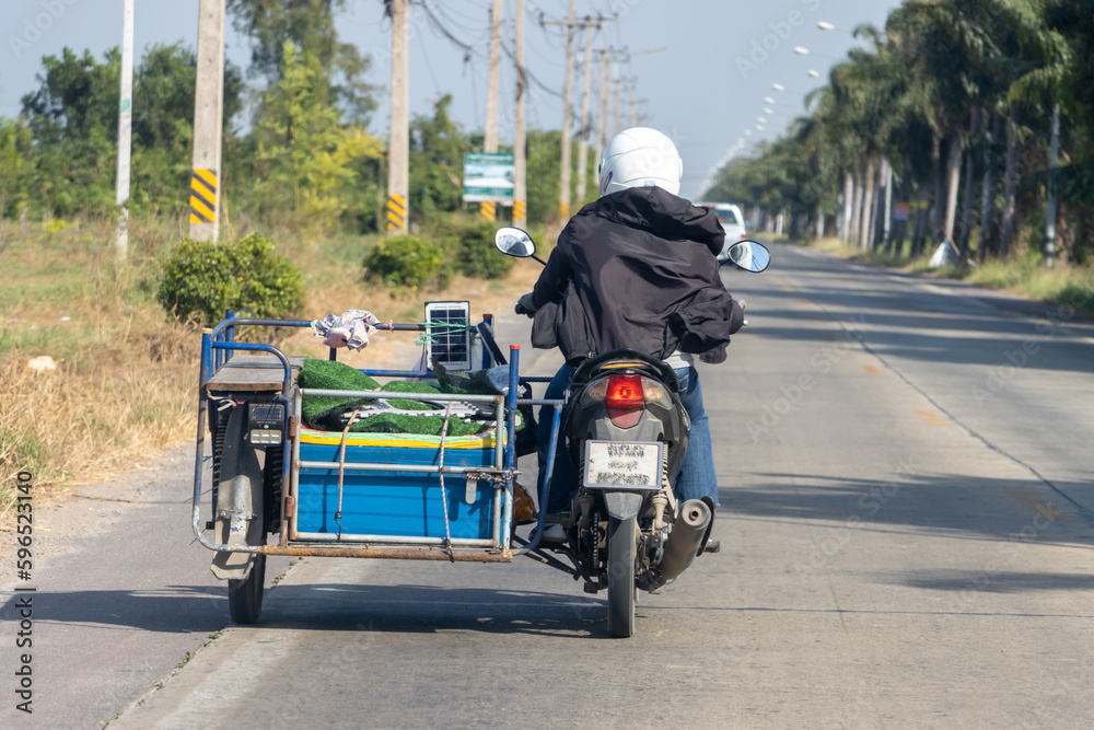 Obraz premium A man carries a load on a sidecar, Thailand