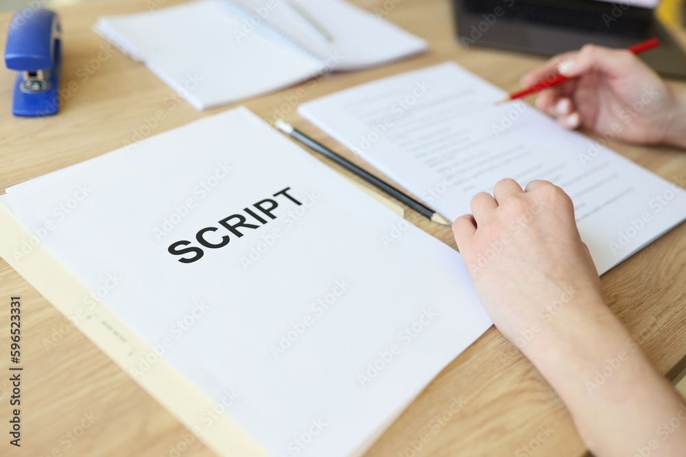 Attentive woman reads script papers editing text with pencil