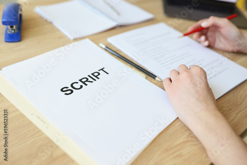 Attentive woman reads script papers editing text with pencil photo