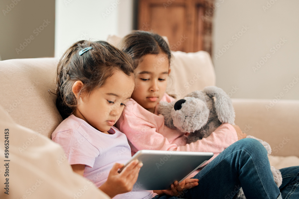 Can we watch something. Shot of two little girls sitting together while using a digital tablet. Can we watch something. Shot of two little girls sitting together while using a digital tablet.