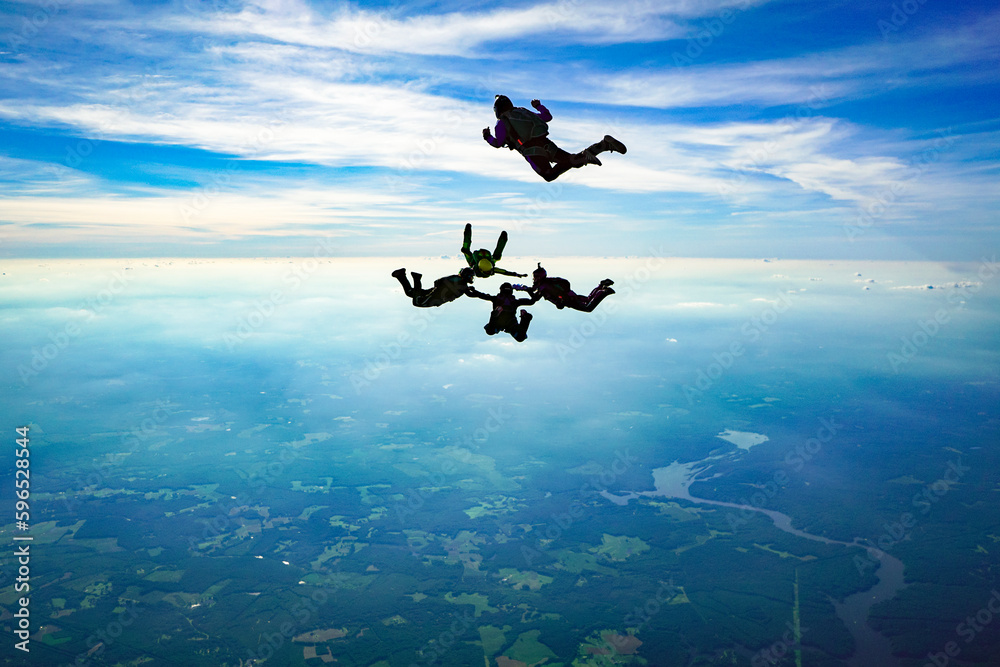 Naklejka premium Skydive formation builds over beautiful landscape silhouette