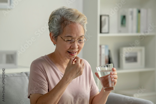 Asian senior woman taking medicine at home, age, medicine, healthcare and people concept