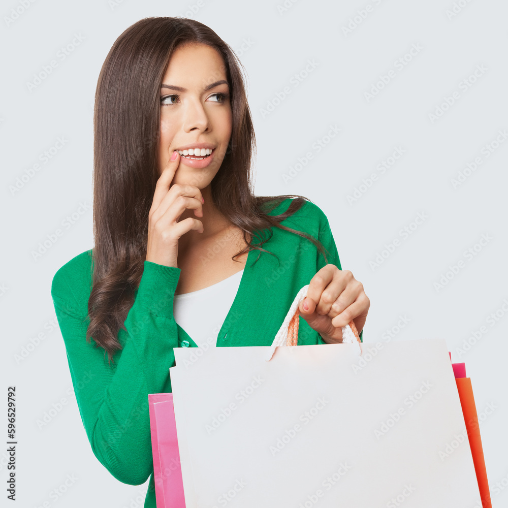 Square image of young asian caucasian woman in green casual cloth wear, sweater hold shopping bags, isolated on light grey gray background. Girl posing at studio. Sales, rebates, discounts deal offers Square image of young asian caucasian woman in green casual cloth wear, sweater hold shopping bags, isolated on light grey gray background. Girl posing at studio. Sales, rebates, discounts deal offers