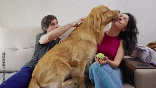 Wallpaper Mural Golden Retriever with joyful couple sitting on couch at home. Dog licking female owner face. Happy Pet owners Torontodigital.ca