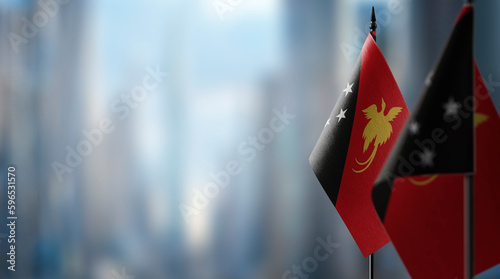 Small flags of the Papua New Guinea on an abstract blurry background