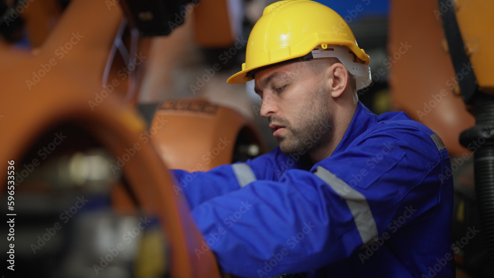 Male engineer checking and fixing robot arm in Advanced Manufacturing Facility. Technology, Robot, Development, Innovation and Industrial concept. Male engineer checking and fixing robot arm in Advanced Manufacturing Facility. Technology, Robot, Development, Innovation and Industrial concept.
