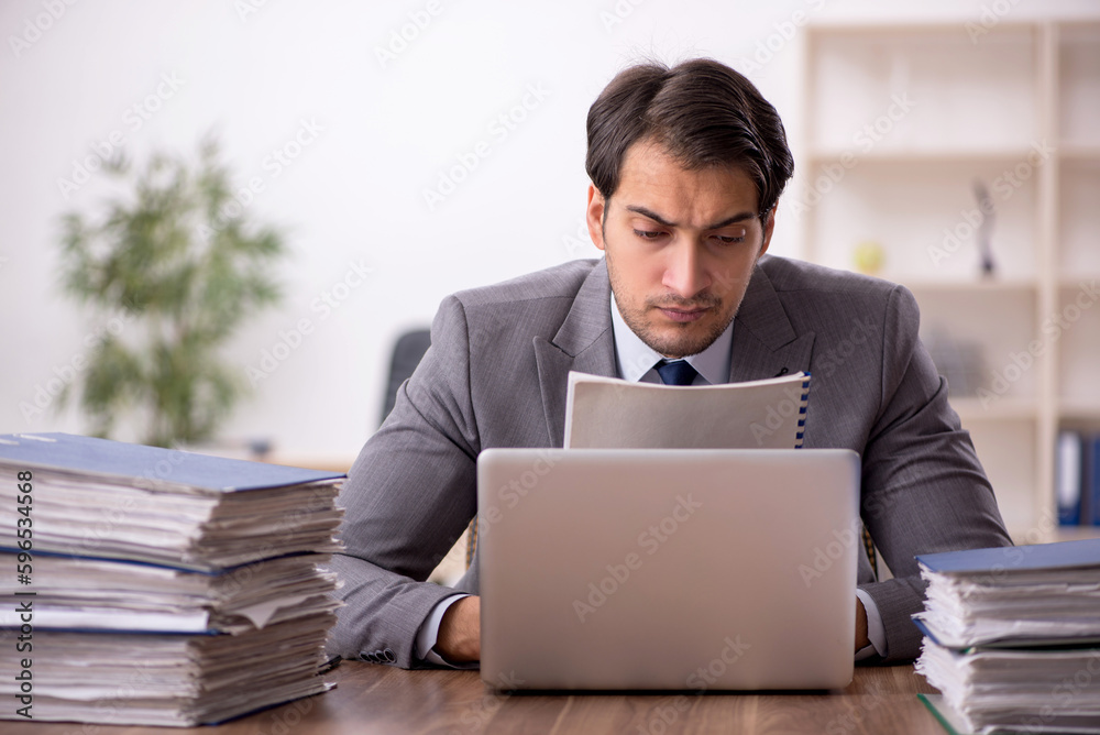 Young male employee and too much work in the office Young male employee and too much work in the office
