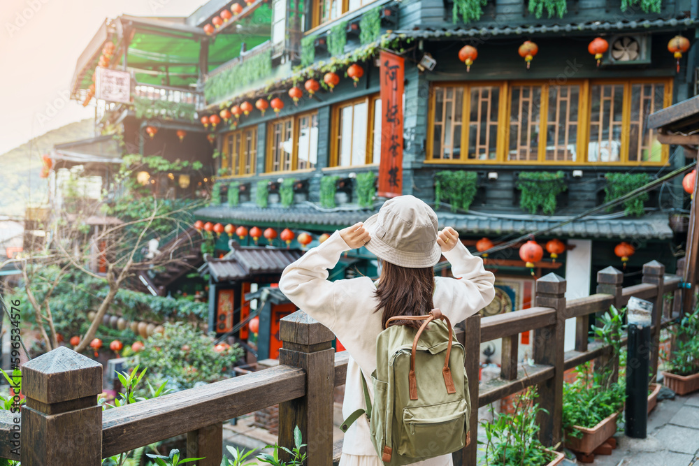 woman traveler visiting in Taiwan, Tourist with hat and backpack sightseeing in Jiufen Old Street village with Tea House background. landmark and popular attractions near Taipei city. Travel concept - obrazy, fototapety, plakaty 