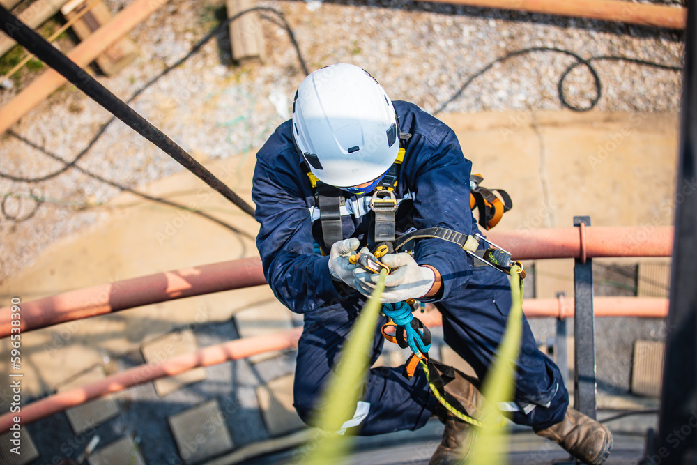 Obraz premium Focus top view male worker down height tank roof rope access safety inspection of thickness storage tank .
