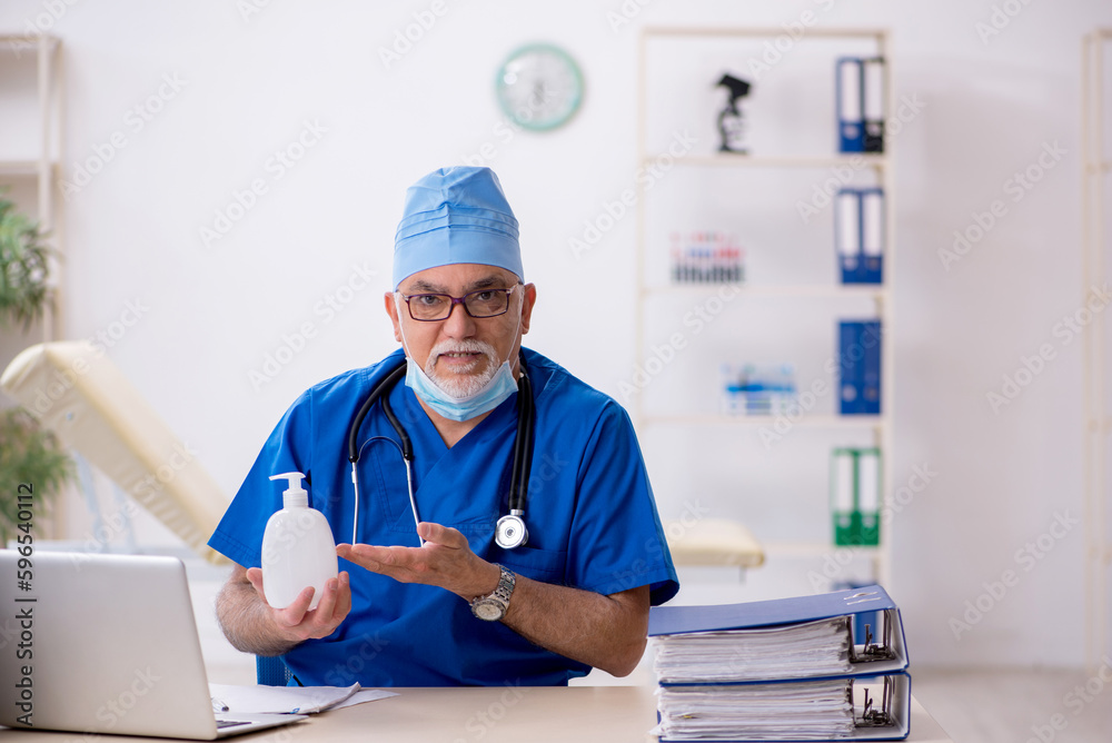 Obraz premium Old male doctor working in the clinic during pandemic