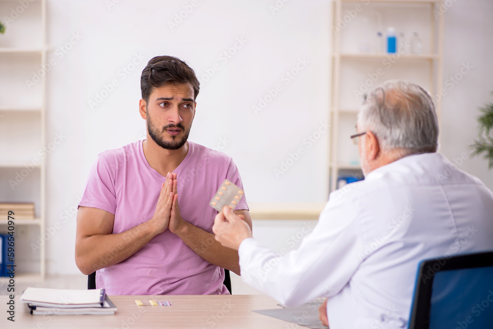 Young male patient visiting old male doctor Young male patient visiting old male doctor