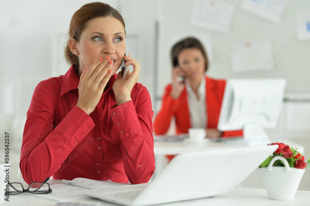 Businesswoman architect with smartphone in modern office with her colleague Businesswoman architect with smartphone in modern office with her colleague