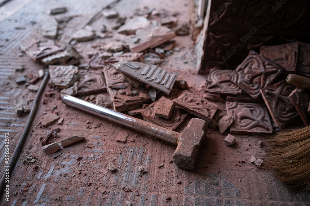 Close-up of hammer with the broken tile on the floor