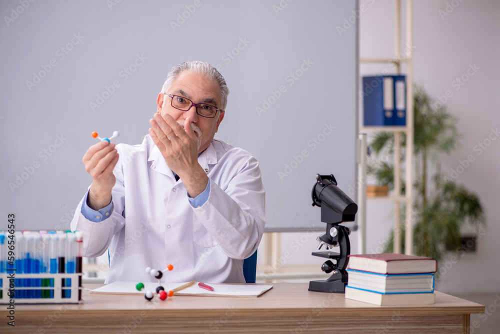 Old male chemist teacher sitting in the classroom Old male chemist teacher sitting in the classroom