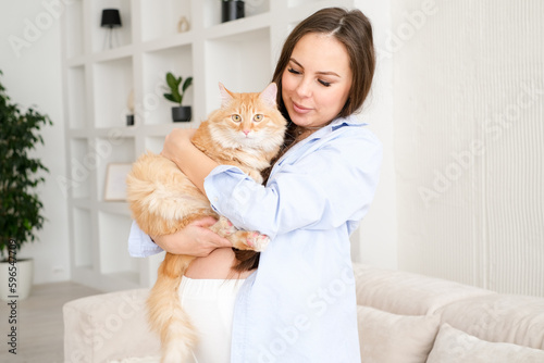 young pregnant woman at home with her red cat. Pet owner at home,