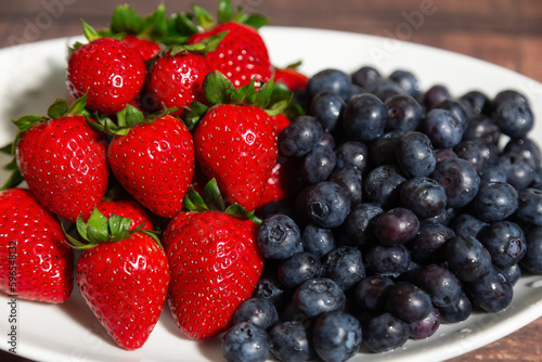 Fresh Bowl of strawberries and blueberries on a wooden table.