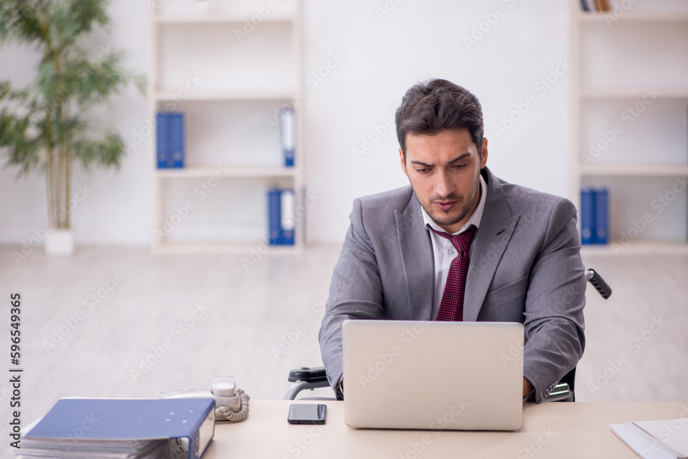 Young employee in wheel-chair working in the office Young employee in wheel-chair working in the office