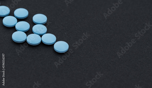 Heap of blue pills on a black table. photo