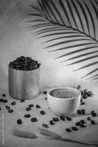 A cup of coffee with coffee beans with blurred background and black and white effect