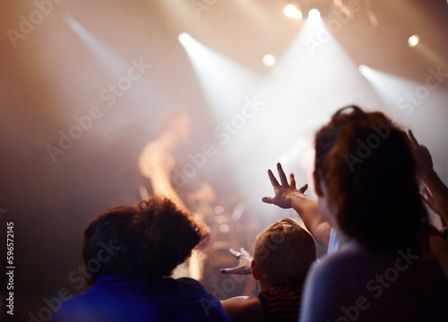 Hands, lighting and excited fans at music festival, crowd watching live band performance with musician on stage. Happiness, excitement and audience in arena, woman fans with hand out at rock concert.