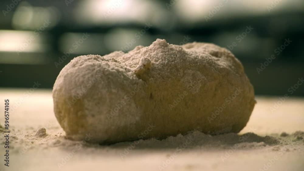 Close up flour raining on pasta dough and hands working the ball of dough. Close up flour raining on pasta dough and hands working the ball of dough.