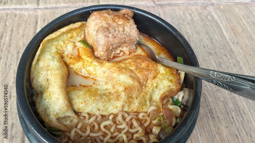 Noodle soup with egg in black bowl on wooden table