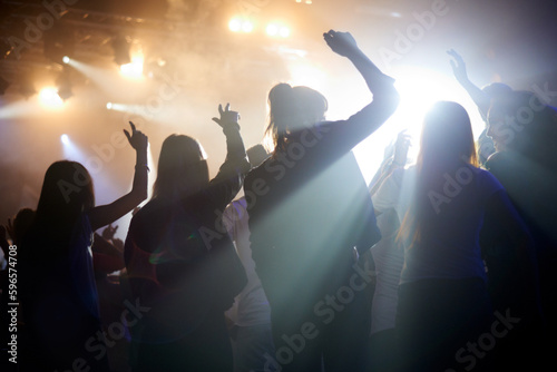 Dance, silhouette of people at music festival from back, lights and energy at live concert event. Dancing, fun and group of excited fans in arena at rock band performance or friends at party together