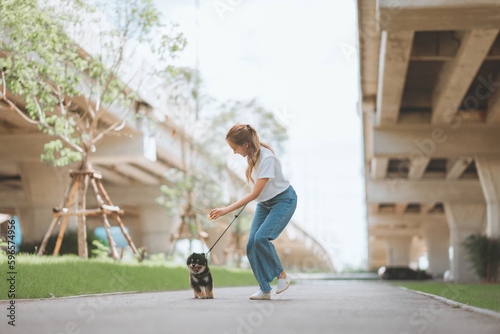 Happy asian woman walking with dog together in park outdoors