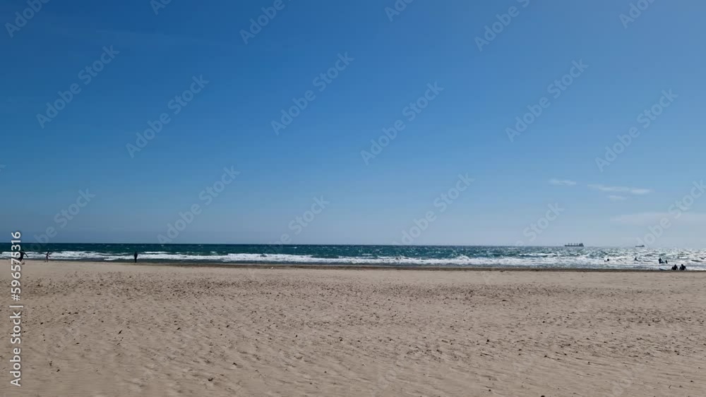 Vacationers on the beach of Castellon in spring. People sunbathe and play on the yellow sand of a Spanish beach on the first warm sunny days.