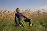 Serie of photos of female model in purple turtleneck and green trousers posing on meadow. Outdoor fashion portrait with natural light.