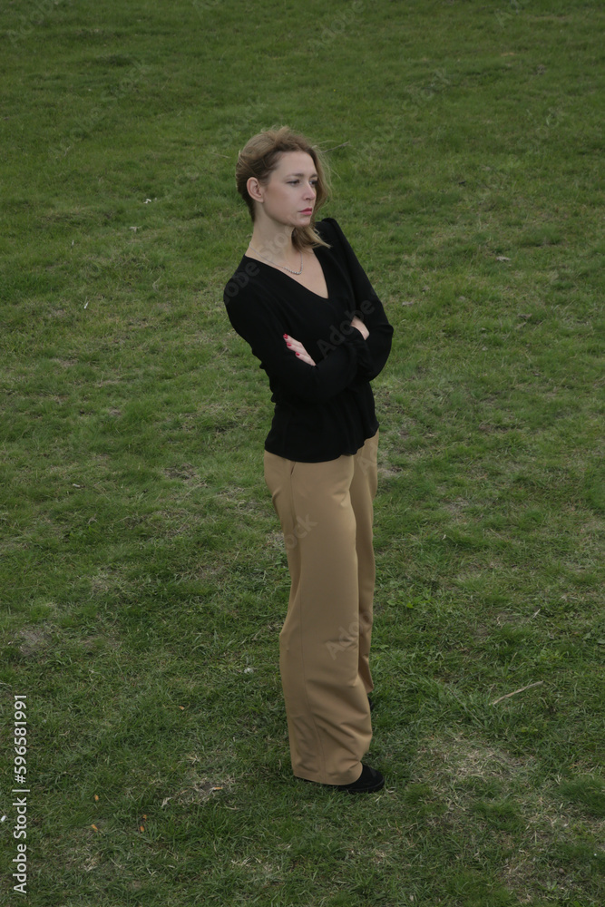 Outdoor fashion portrait of Caucasian woman in wide leg beige pants and black blouse