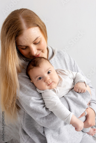 Mom and baby play on the bed. Mother and son, happy family, beautiful blonde girl and cute baby at home.