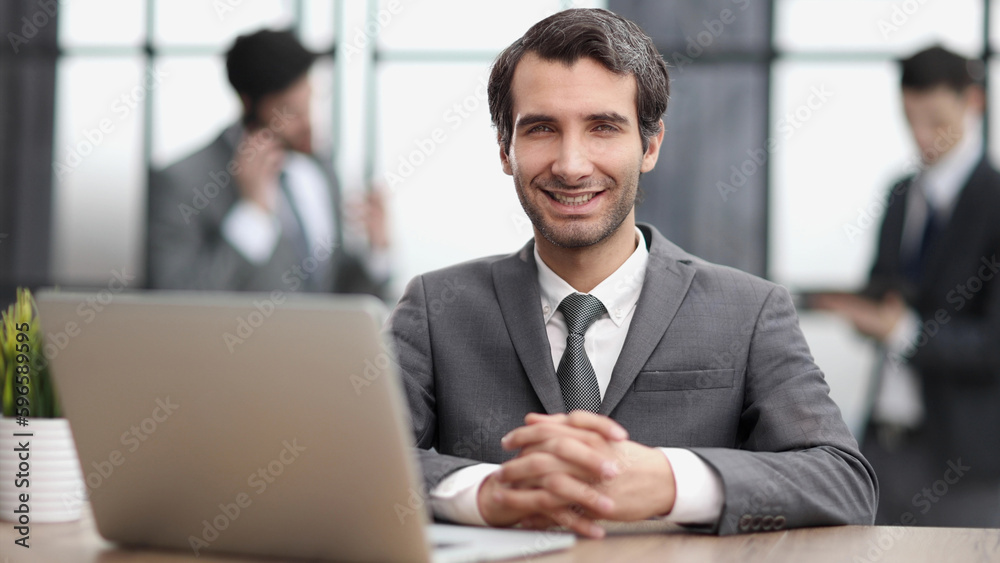 Business man sitting at his desk in the office with a laptop