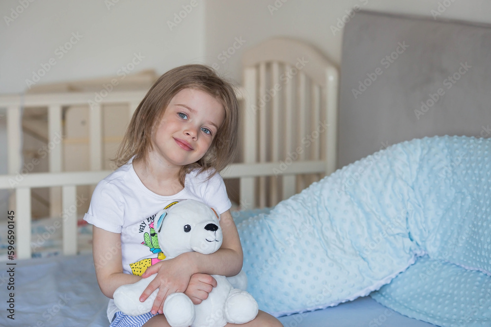Family, childhood and love. Portrait of a beautiful little girl in bed in a bright bedroom. A child with a teddy bear in his hands. Childhood. Family, childhood and love. Portrait of a beautiful little girl in bed in a bright bedroom. A child with a teddy bear in his hands. Childhood.