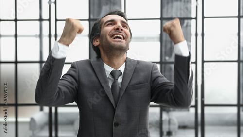 Businessman closeup in modern office, portrait successful man celebrating victory and good achievement results